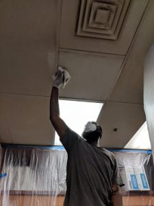 man washing ceiling tiles