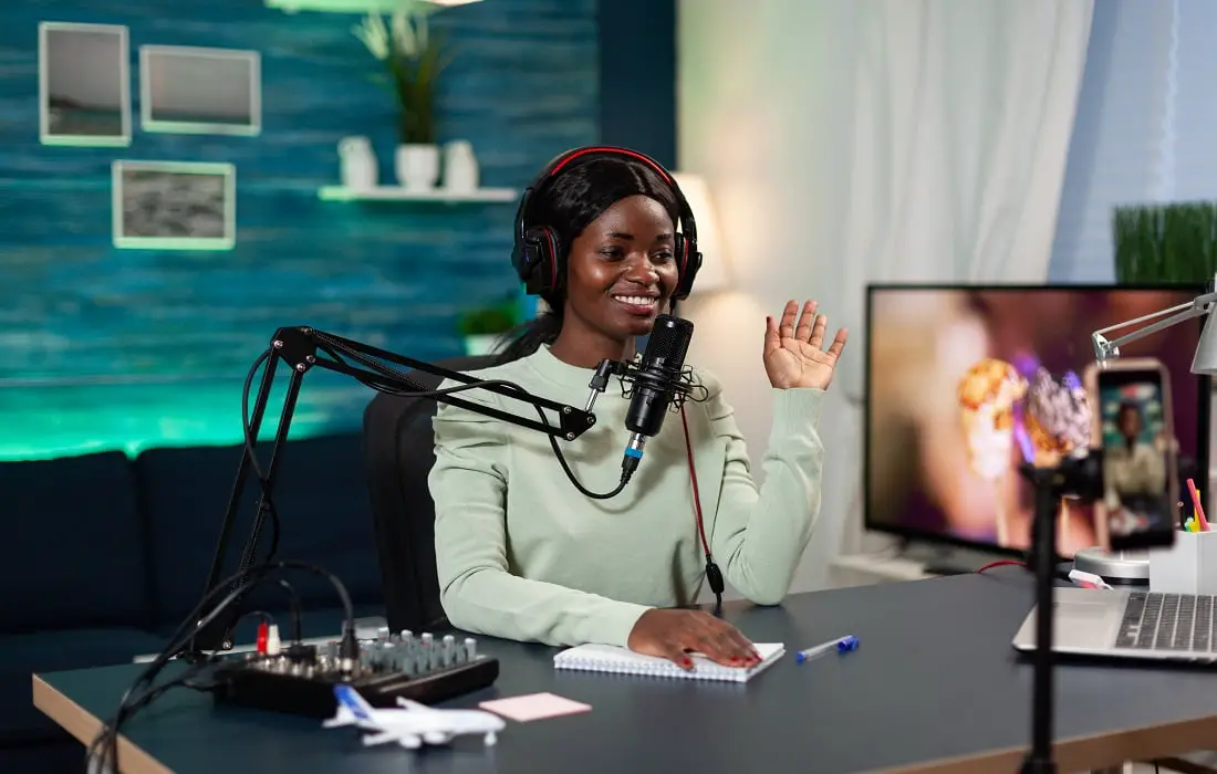 Woman creator sitting at table in streaming studio greeting subscribers