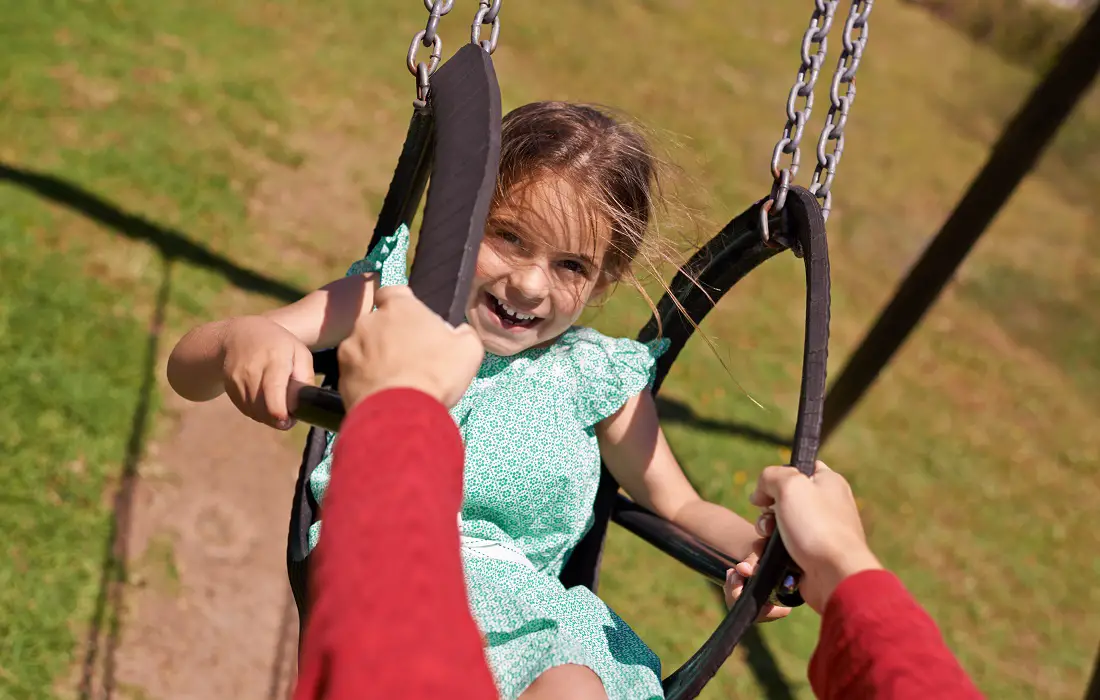 portrait-girl-and-parent-on-swing-in-park-for-summer-vacation